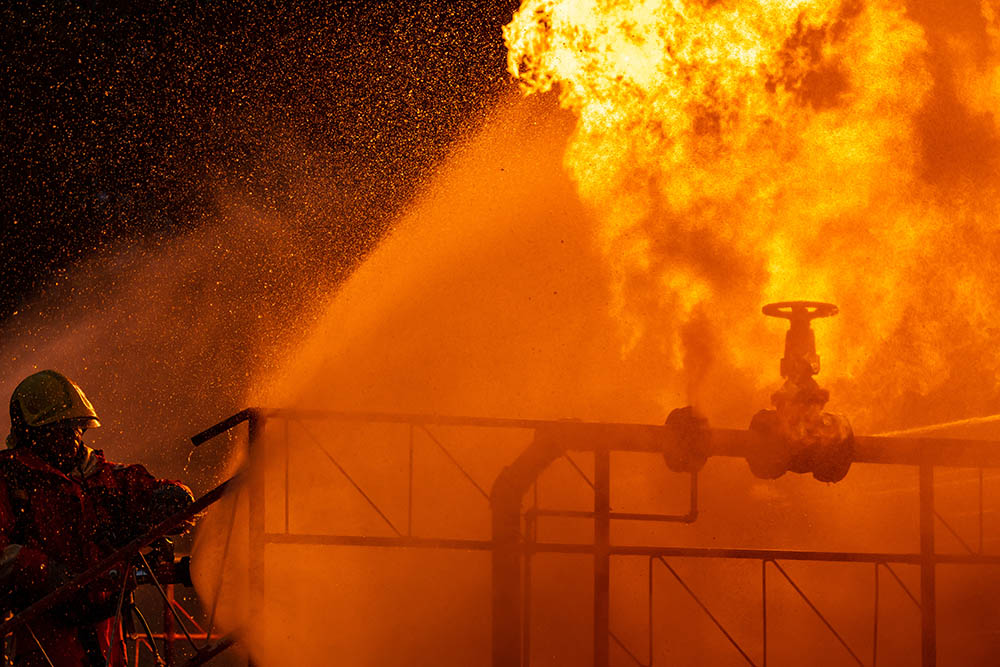 A firefighter attempts to extinguish a fire inside of a factory.