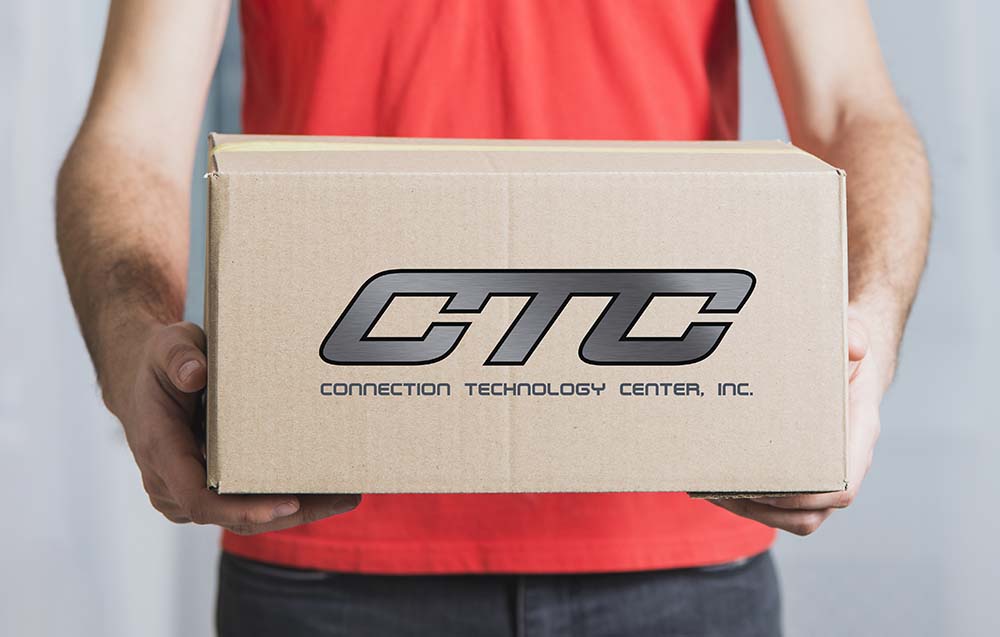 A man wearing a red short sleeve shirt holding a brown cardboard, CTC-logo shipping box
