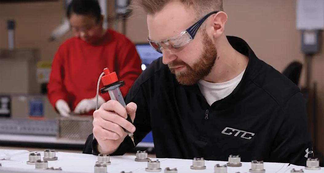 A CTC employee in safety glasses assembling mounting magnets.
