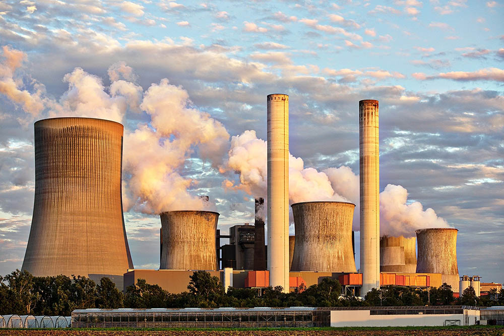 Power Plant Cooling Towers with smoke against a blue cloudy sky